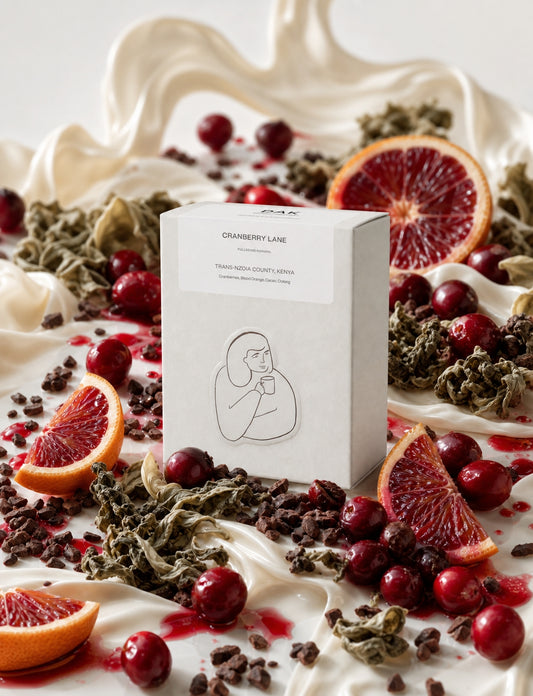 Cranberry Lane tea packaging on a decorative plate with cranberries and oranges