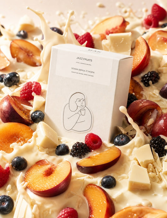 Fruit bath with white chocolate drizzle and a box of DAK Jazz Fruits coffee on top